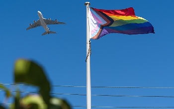 Progress flag flying in the sky with a plane in the background